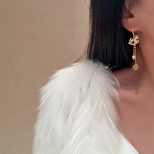 Orecchini in stile cinese con cavallo a dondolo, perle e nappe di monete su modella