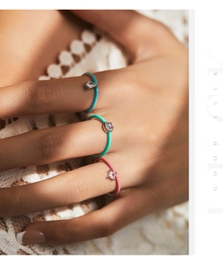 Close-up of three stacked S925 silver enamel rings with colorful gems and lace background