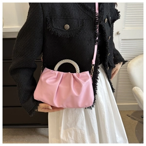 Detailed side view of pink pleated cloud bag with pearl handle on model in stylish setting