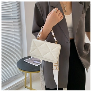 Detail of cream white quilted crossbody bag with resin chain and patterned fabric strap