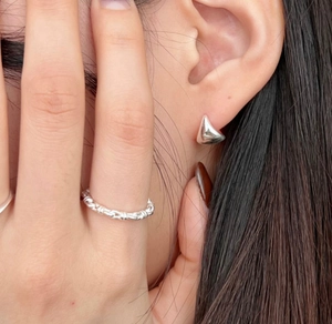 Close-up of minimalist S925 sterling silver oval hoop earrings and a twisted texture ring