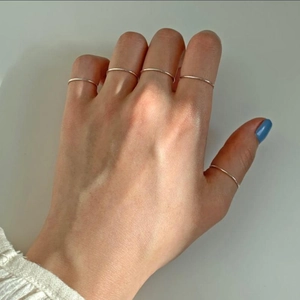 Detailed view of minimalist S925 sterling silver thin rings layered on model fingers