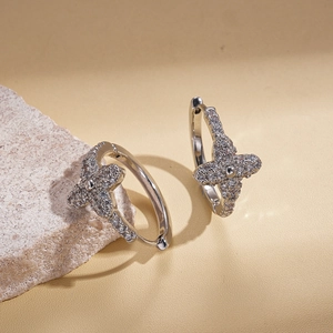 Detail view of silver zircon star hoop earrings resting on a natural textured stone