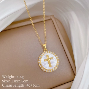 Close-up of gold cross pendant with white pearl shell and crystals on silk background