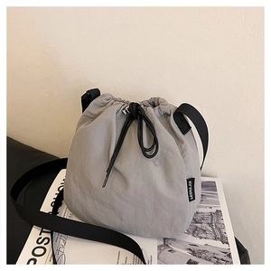 Detail of light grey drawstring bucket bag made of waterproof nylon with black strap