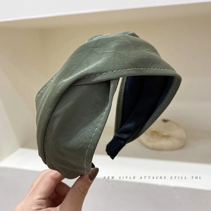 Detail of olive green PU leather headband with criss-cross knot and white stitching