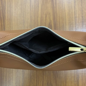Top view of caramel brown leather saddle bag interior with black fabric lining and gold zipper