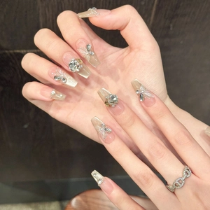 Dettaglio di unghie finte di lusso con sfumatura occhio di gatto, perle e nail art farfalla