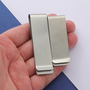 Detail of long and short brushed stainless steel money clips held by hand for scale