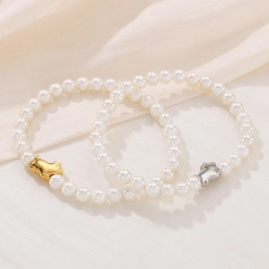 Elegant pearl bracelet with gold and silver pig charms on silk background for women