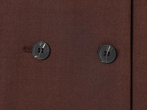 Détail du tissu sergé marron foncé et des boutons croisés avec motif marbré