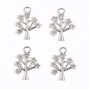 Close-up of four silver tree pendants with inlaid crystals for DIY jewelry making