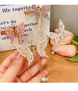 Detail view of handmade butterfly hair clip with pastel pearls and dangling golden tassels
