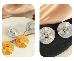 Detail of round textured earrings in gold and silver finish with concentric circle patterns