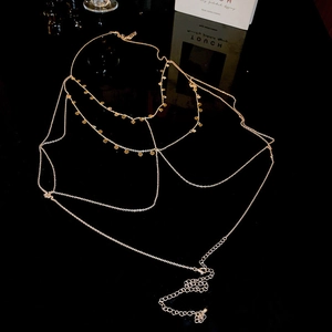 Detail of layered gold body chain featuring small metal discs on reflective surface