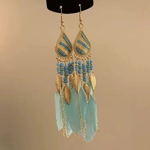 Detail of vintage bohemian earrings with light blue feathers and golden leaf tassels