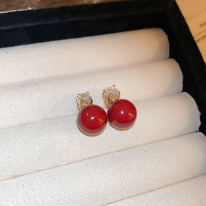 Detailed shot of red pearl stud earrings with zircon inlay in a white velvet jewelry box