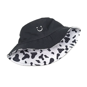 Reversible bucket hat with black smile embroidery and cow pattern lining for sun protection