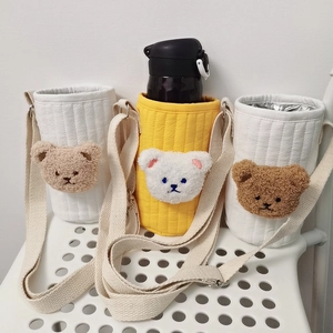 Detailed view of quilted cotton bottle bags with plush bear heads and shoulder straps