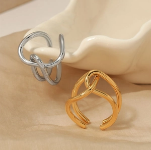 Detail of twisted geometry rings in gold and silver finish on silk fabric