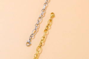 Close-up of gold and silver textured chain necklaces with lobster clasps on pink background