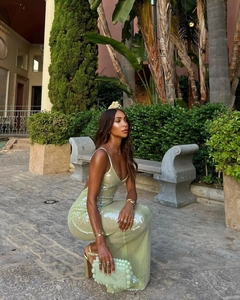 Close-up of a light green sequined backless slim maxi dress with beaded clutch in a garden