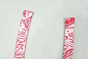Détail de la lanière à nouer au dos avec un motif textile abstrait imprimé rouge et blanc