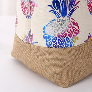 Detail of canvas shopping bag with jute bottom stitching and colorful pineapple print