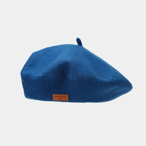 Close-up of a navy wool beret featuring a brown leather patch with LOVE STYLE text