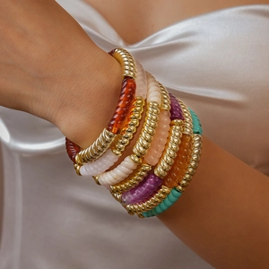 Gros plan de bracelets en perles acryliques colorées avec entretoises dorées au poignet