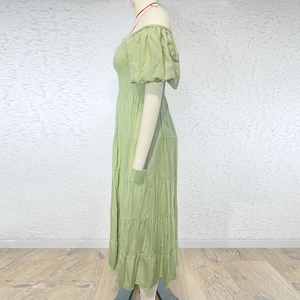 Detail view of tiered skirt hem and light green smocked bodice with puff sleeves