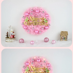 Pink Christmas wreath with LED lights and gold Merry Christmas sign in warm holiday scene