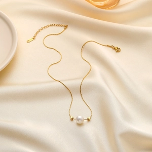 Elegant 18K gold plated titanium necklace with white pearl pendant on silk fabric