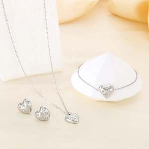 Macro shot of silver heart jewelry set featuring necklace bracelet and stud earrings