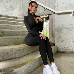 Detail of high-neck zipper sports jumpsuit on model sitting on outdoor steps