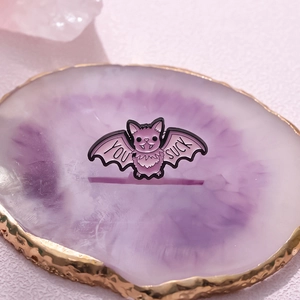 Detail of cute purple enamel bat pin with 'YOU SUCK' text on a crystal base