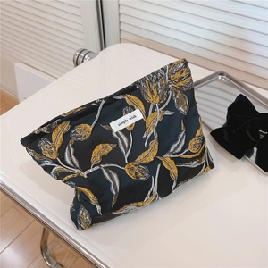 Nahaufnahme goldener Tulpenstickerei auf einer schwarzen Jacquard-Kosmetiktasche