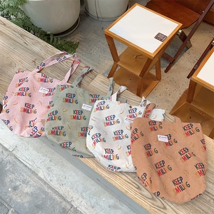 Detailed texture of colorful corduroy tote bags with Keep Smiling embroidery on wooden bench