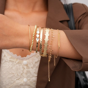 Close-up of 7-piece gold geometric bracelets featuring crystal accents on a model wrist