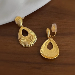 Golden drop-textured hollow shell earrings displayed on a rustic wood surface