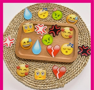Collection of colorful acrylic emoji charms featuring various expressions on a wooden tray