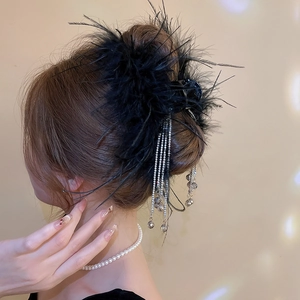 Detail of black feather hair claw with sparkling rhinestone tassels in elegant hairstyle