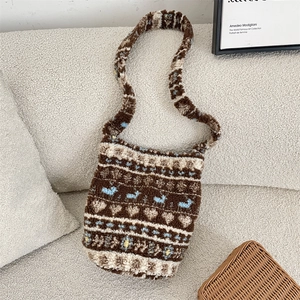 Detail of plush brown and beige bucket bag with reindeer pattern on a white sofa