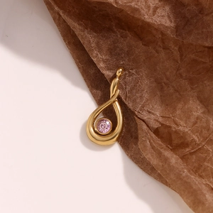 Macro detail of 18K gold teardrop pendant featuring a centered pink zircon stone