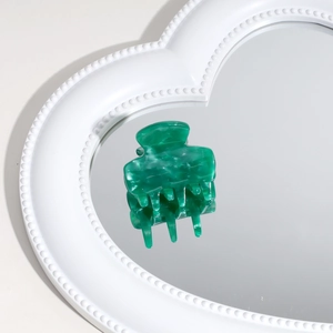 Elegant green marble acetate hair claw clip displayed on a heart-shaped mirror surface