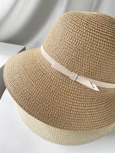 Detail of straw woven texture on wide brim sun hats with delicate ribbon bow decoration