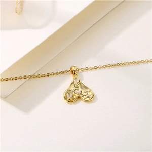 Golden heart pendant necklace with zircons on a minimalist beige surface background