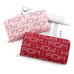 Detail view of pink and red long zipper wallets with textured faux leather and letter print