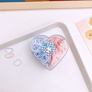 Detail of high-elastic kids hair bands in a heart-shaped case with cute bunny sticker