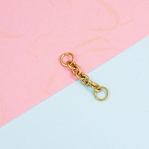 Golden stainless steel chain extender with open rings on pink and blue background